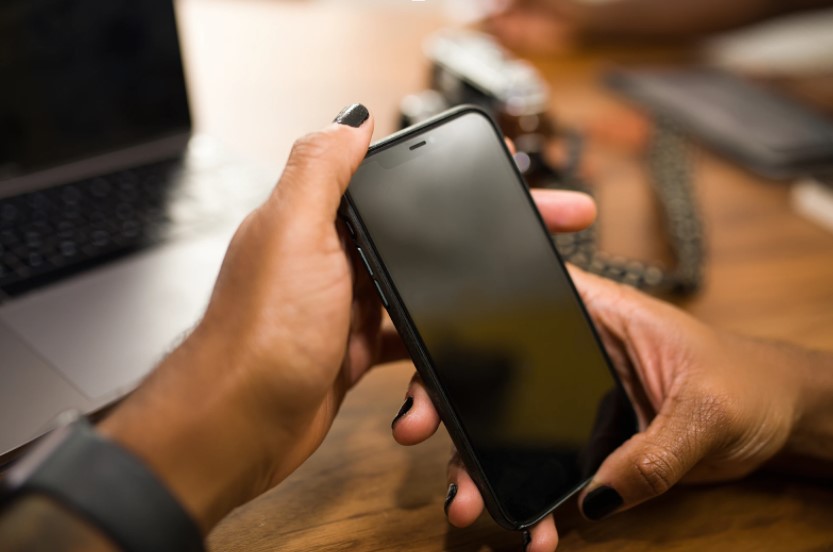 virtuerenity-resources Person holding a black smartphone with a blank screen.